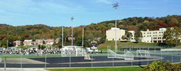 Students and staff wait on the field of Chuck Knox Stadium while Quaker Valley High School (at right) is searched after a bomb threat on October 29, 2013.